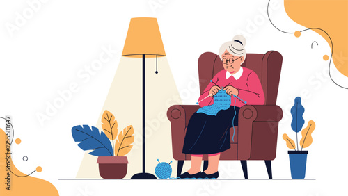 Elderly woman with gray hair sitting in a cozy armchair and knitting a blue scarf under the warm light of a floor lamp in her living room.
