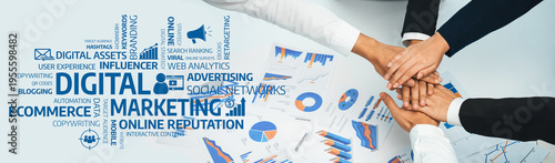 Foto A group of hands collaboratively resting on digital marketing materials, showcasing charts and pivotal keywords that represent strategies for online growth and influence