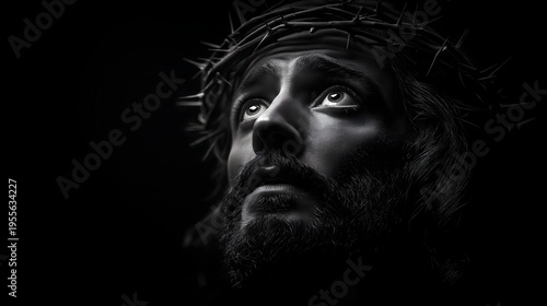 Jesus Christ wearing a crown of thorns looking upward on black background