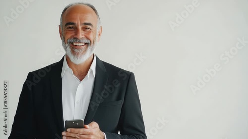 A man in a suit and tie, holding a phone to his ear with a smile on his face. He appears to be engaged in a pleasant conversation or is receiving good news.