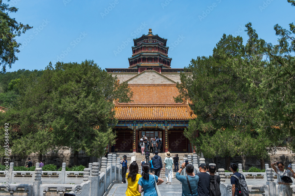 Obraz premium A bustling scene of tourists crossing a stone bridge leading towards the majestic Tower of Buddhist Incense at the Summer Palace in Beijing, China - 27 May 2025