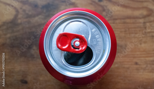 Cuadro en lienzo Top view of an opened red and silver aluminum soda can with a red pull tab, resting on a textured wooden background