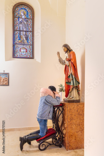 фотографія A vertical full length shot of a woman in a denim jacket kneeling on a red prie-