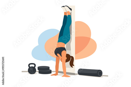 Woman performing handstand exercise against wall with fitness equipment.