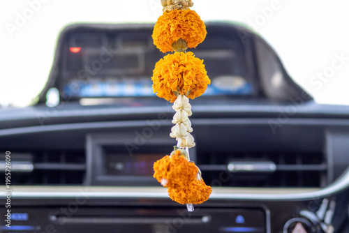 Traditional Thai flower garland swinging from a rearview mirror in a moving taxi for luck and protection