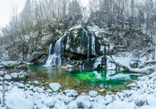 Emerald green water of river spring in the snowy winter