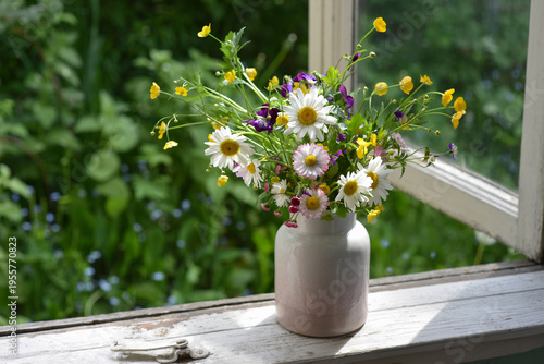 A bouquet of spring wildflowers in a vase. Still life on the windowsill of an old village house, summer cottage. Country life aesthetics