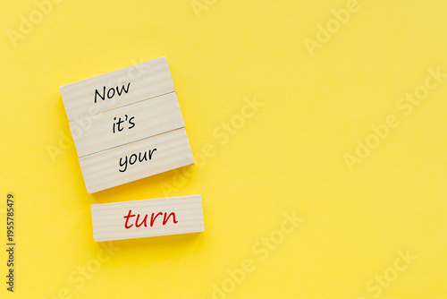 Tableau sur toile Wooden blocks with the text 'Now it's your turn' on a bright yellow background