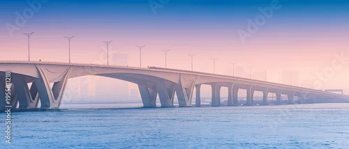 Panel kuchenny z motywem bridge providing a modern architectural link over calm water during an atmospheric morning in Abu Dhabi. Urban silhouettes visible in the distance