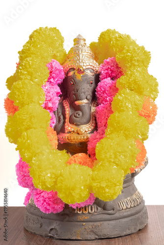 Ganesha idol wrapped in bright yellow and pink flower garland for Hindu festival decoration