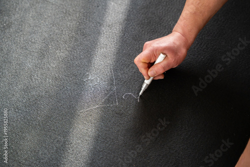Принти на полотні Close up of man marking measurement lines on black flooring underlay with white