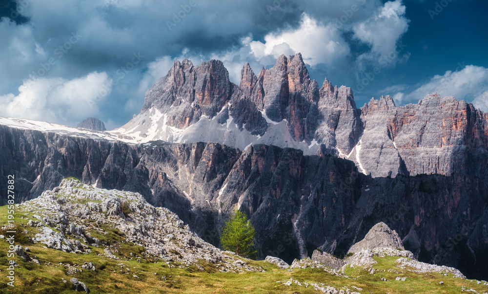 Obraz premium Beautiful alpine mountains in summer evening in Dolomites, Italy. Colorful landscape with mountain peaks, rocks, tree, trail, green grass, dramatic blue sky with clouds. Nature. Alps in spring