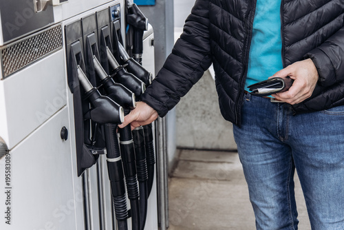 Tableau sur toile Man holding fuel nozzle at gas station refueling car