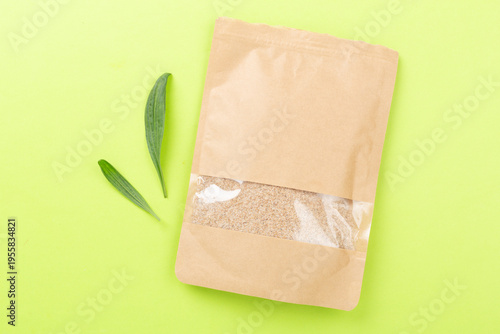 Fotografía Psyllium husk powder with fresh leaves on color background, top view