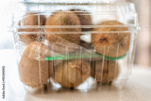 Green fuzzy kiwi fruit in plastic container box from store supermarket macro closeup