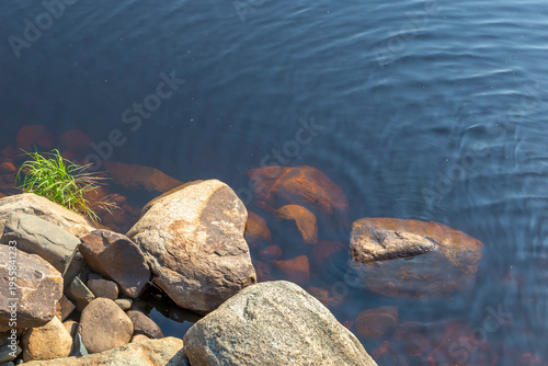 Small granite boulders lie on the shore of a peat lake.