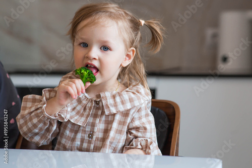 Obraz na płótnie A cute little girl is trying broccoli