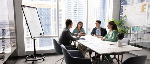 Diverse corporate team holding open discussion by conference table collaborating on shared project exchanging ideas insights on strategic development interacting on staff briefing in modern boardroom
