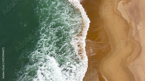Top down, drone view of waves breaking in the sand with strong colours and beautiful patterns.