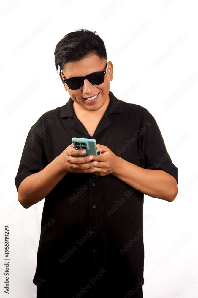 Fototapeta premium Young man wearing sunglasses smiling while texting on smartphone isolated on white background
