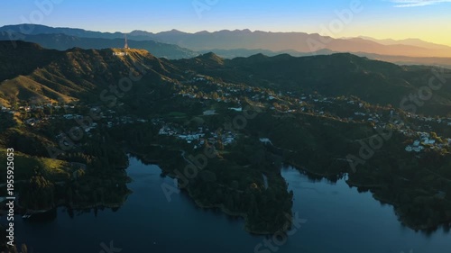 Los Angeles, California USA - FEBRUARY 22, 2026: Aerial view of lake in foreground with Hollywood Hills and distant mountains under sunset with very low sun creating warm glow and deep shadows.