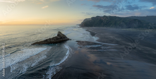 Foto Aerial view of waves crashing against a rock formation on the beach at Karekare Beach in Auckland, New Zealand