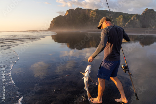 Photos A fisherman displays his catch of the day, a large snapper, on the beach at Karekare Beach in Auckland, New Zealand