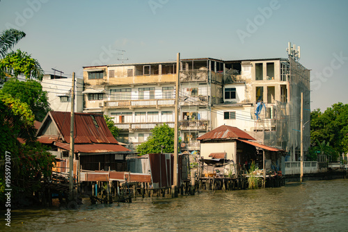 Photos Traditional wooden houses on stilts along the river with old concrete buildings in Bangkok, Thailand