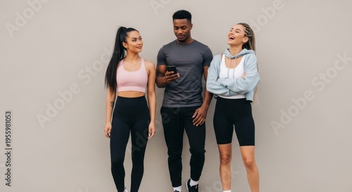 Three friends laughing together in casual workout clothes standing indoors