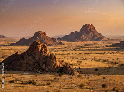 Golden hour illuminates the rugged Spitzkoppe mountains in the Namib Desert, Namibia, creating a breathtaking landscape.