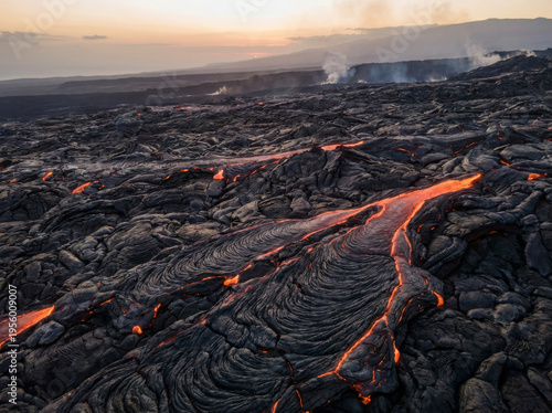 Molten lava flowing across a rugged volcanic landscape at sunset, creating a dramatic natural spectacle.