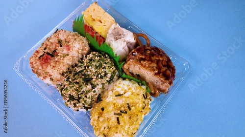 回転する俵おにぎりのお弁当 パック入り 青背景