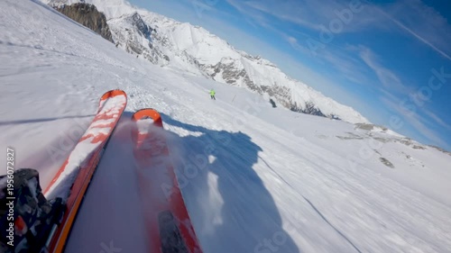 Low angle POV of skier going fast down the hill on sunny clear day . Skier own skis visible in the foreground	