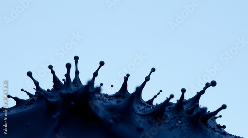 Deep blue liquid splashes dynamically forming sharp crown-like droplets against a light blue background capturing motion