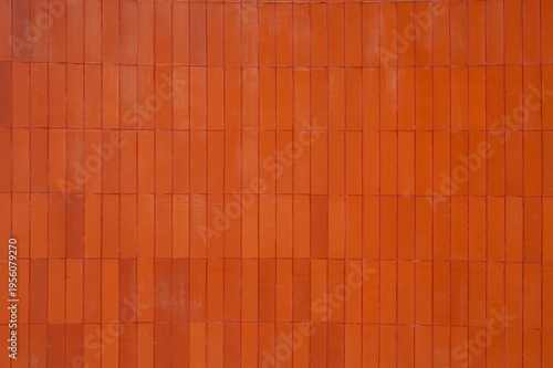 Modern architectural background featuring vertical orange ceramic wall cladding.