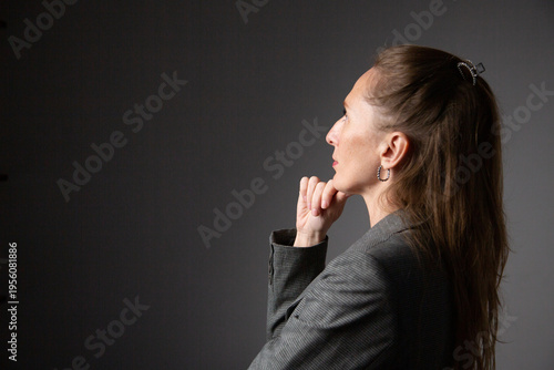 A portrait of a woman in a business suit, deep in thought, holding her chin in her hand