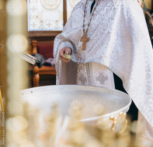 Orthodox priest with sponge performing baptism ceremony in church