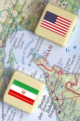 American and Iranian flags on a plastic blocks near the Strait of Hormuz on a map, close-up.