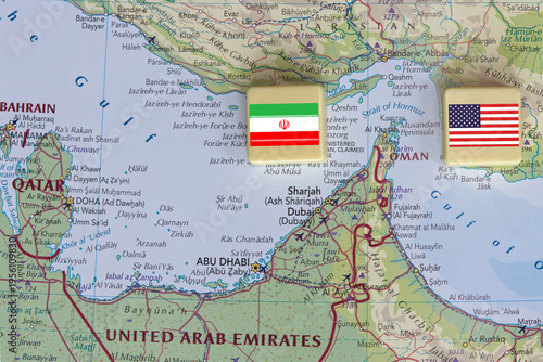 American and Iranian flags on a plastic blocks near the Strait of Hormuz on a map, close-up.
