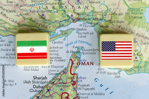 American and Iranian flags on a plastic blocks near the Strait of Hormuz on a map, close-up.