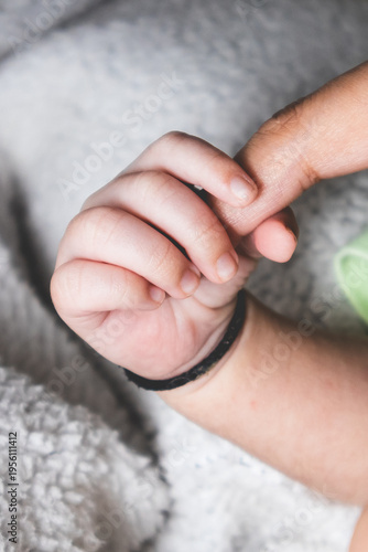 Newborn baby holding parent finger close up, love and bonding concept