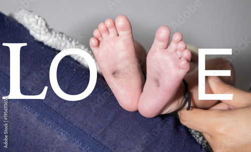 Newborn baby feet with parent hands and love text, family bonding and parenthood concept
