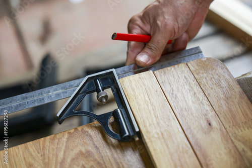 Obraz na płótnie Focused carpenter hand using combination square tool to precisely measure and mark line on wood plank