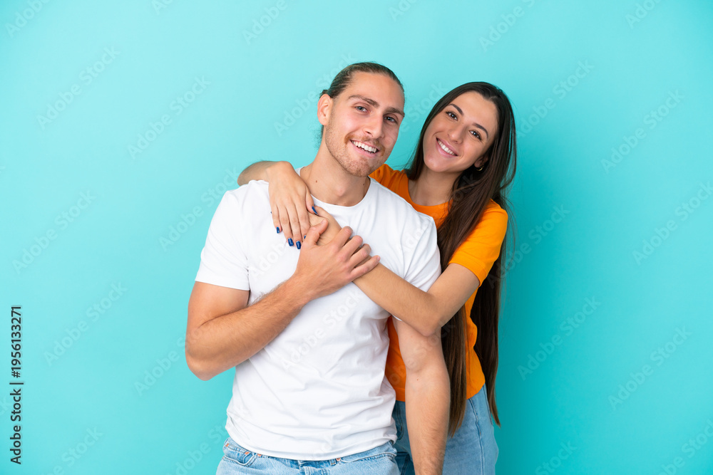 Naklejka premium Young caucasian couple isolated on blue background laughing and hugging