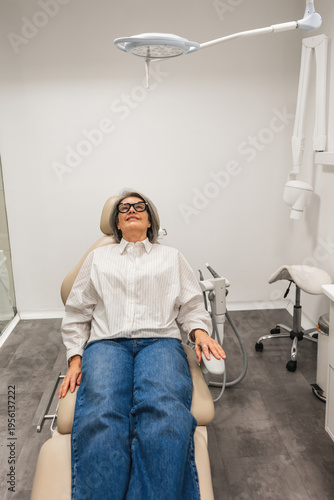 Senior woman patient resting comfortably in a dental chair, preparing for an oral hygiene check up or treatment