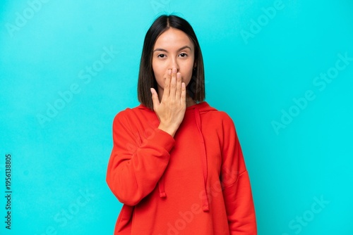 Young caucasian woman isolated on blue background covering mouth with hand