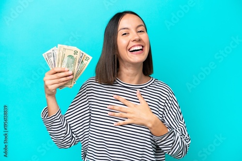 Young caucasian woman taking a lot of money isolated on blue background smiling a lot