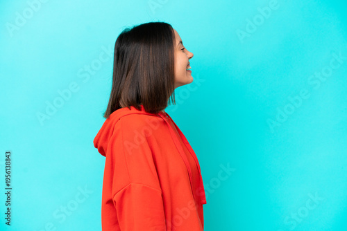 Young caucasian woman isolated on blue background shouting with mouth wide open