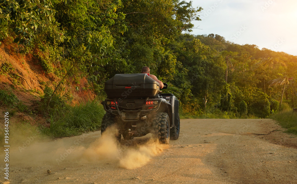 Fototapeta premium A man engages in extreme ATV riding on mountains in the evening