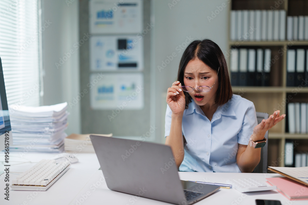 Obraz premium Young businesswoman with a shocked expression reacting to an unexpected data problem on her laptop computer, causing confusion and frustration in a modern office setup